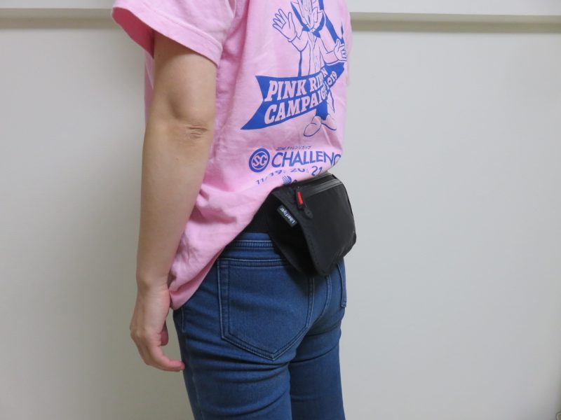 セキュリティポーチの「セキュリポラージサイズ」を女性が服の上の背中側につけた様子