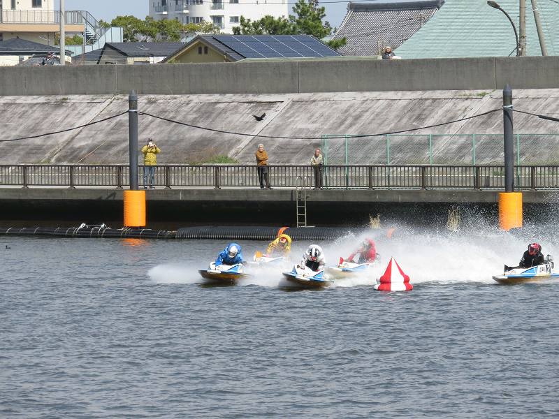 首都高速の下の道から見た江戸川競艇場の競争水面1マーク側を、選手たちが旋回するようす